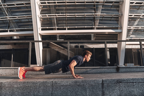full length of man keeping plank position while exercising outdoors  - Foto, immagini