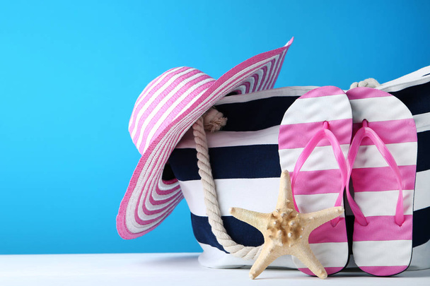 Summer bag with flip flops and hat on blue background - Fotó, kép