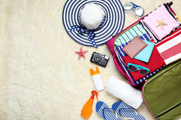 Koffer met kleding, paspoorten en zonnebrandcrème flessen geopend - Foto, afbeelding