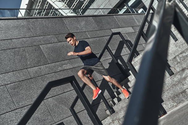 full length of man in sports clothing running on stairs in street  - Foto, Imagen
