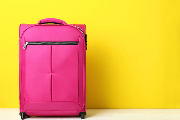 Pink suitcase on yellow background, travel concept - Photo, image