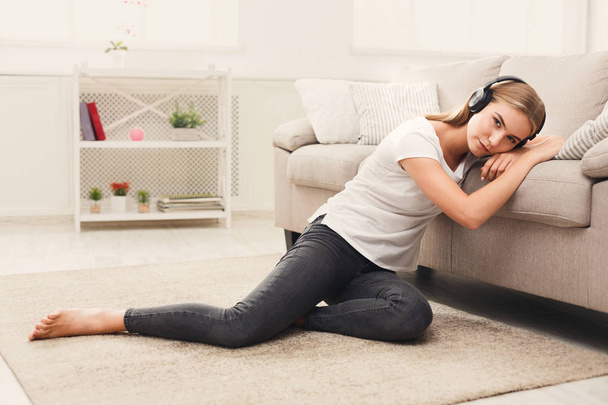 Young sad woman in headphones on floor - Foto, imagen