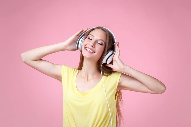 Portrait of young woman with headphones on pink background - Foto, Imagem