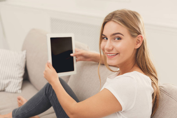 Happy young girl with tablet sitting on couch - Photo, image