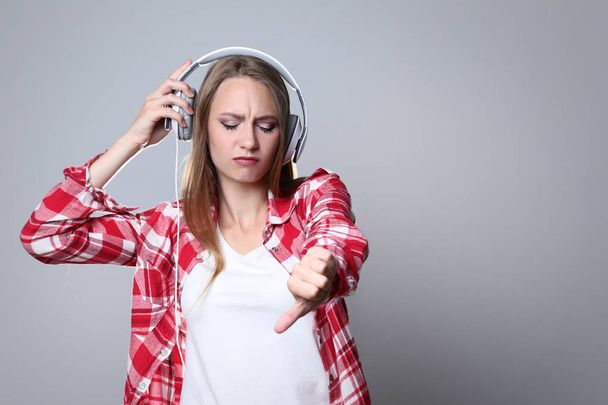 Young woman with headphones on grey background - Zdjęcie, obraz