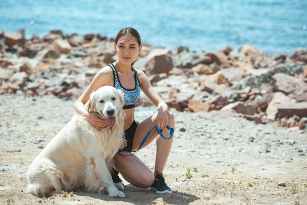 asian woman sitting with golden retriever on beach  - Foto, immagini