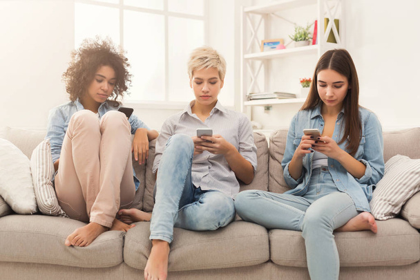 Three female friends using smartphones at home - Zdjęcie, obraz