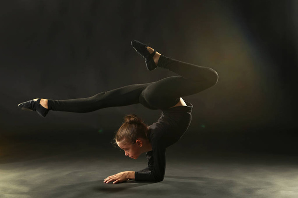 Young girl gymnast on black background - Foto, Imagen