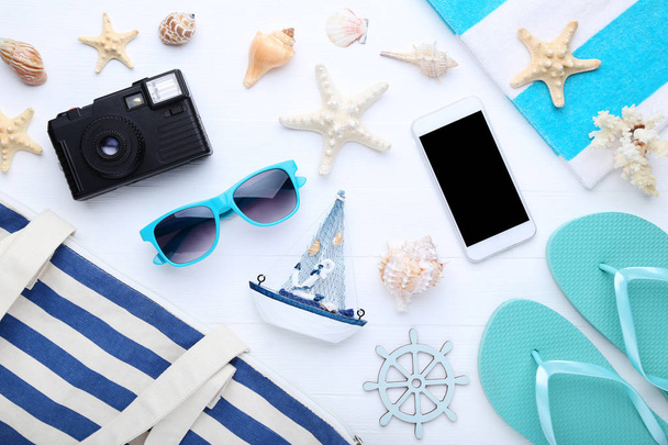 Beach accessories with seashells and smartphone on wooden table - Zdjęcie, obraz