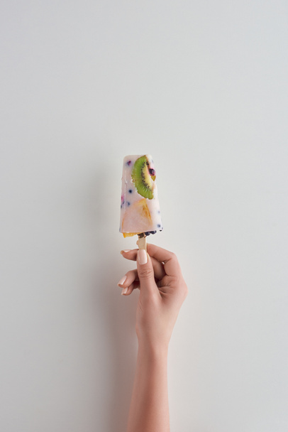 обрезанный снимок человека, держащего свежее фруктовое фруктовое мороженое на сером
  - Фото, изображение