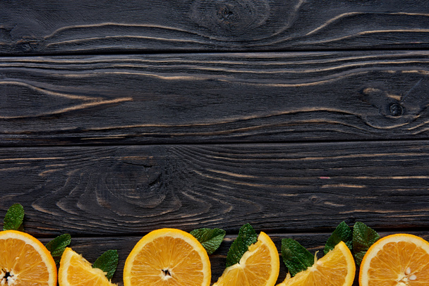 top view of fresh orange slices and mint leaves on wooden background - Photo, Image
