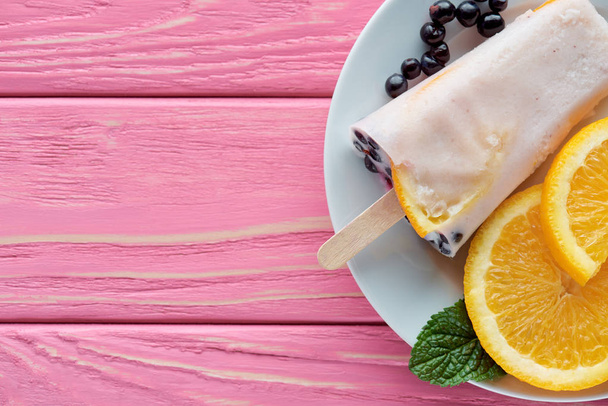 сверху вид на вкусное домашнее мороженое с фруктами и мятой на тарелке на розовом деревянном столе
 - Фото, изображение