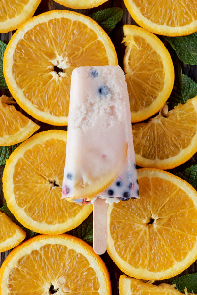 вид зверху на гастрономічне домашнє морозиво з фруктами та ягодами на апельсинових скибочках
  - Фото, зображення