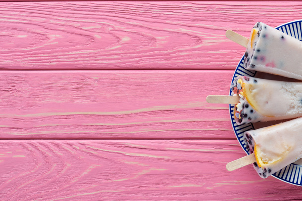 vista superior de doces saborosos picolés caseiros com frutas e bagas no prato na mesa de madeira rosa
  - Foto, Imagem