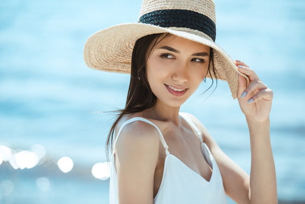 selective focus of attractive asian woman in straw hat looking away - 写真・画像