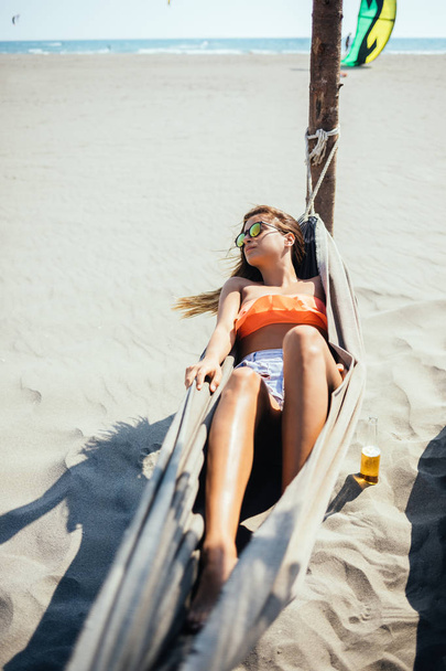 Beautiful caucasian brunette lying on hammock at beach and enjoying summer. - Zdjęcie, obraz