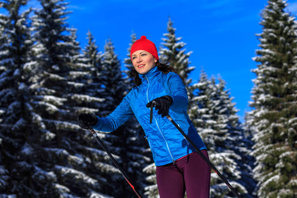 Kobieta biegająca na nartach biegowych lub langlauf biegająca w chłodnym lesie - Zdjęcie, obraz