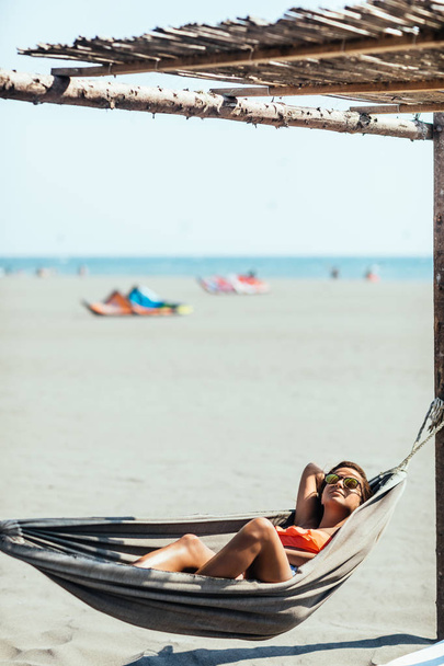 Beautiful caucasian brunette lying on hammock at beach and enjoying summer. - Fotó, kép