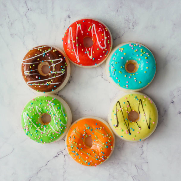 сладкие красочные пончики расположены в виде круга на мраморном фоне. Минимальная концепция питания
  - Фото, изображение