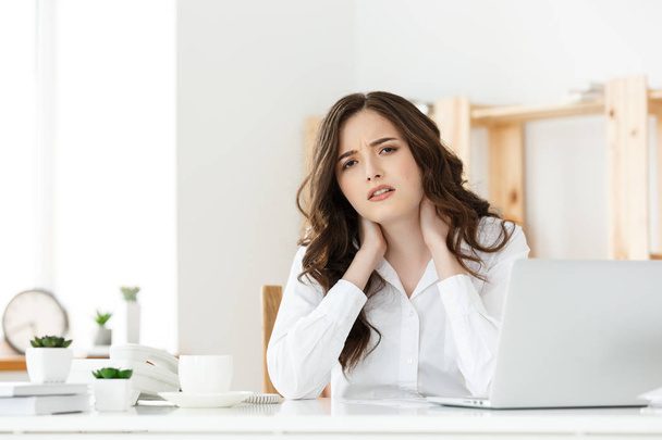Cansada jovem empresária sofrendo de muito tempo sentado na mesa de computador no escritório
 - Foto, Imagem