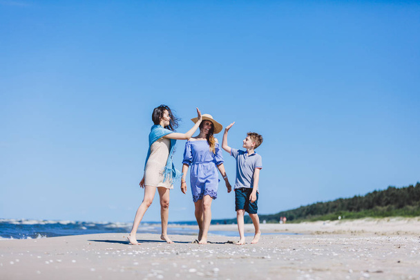 Mother with children walking by sea on hot summer day. Family bonding. - Photo, Image