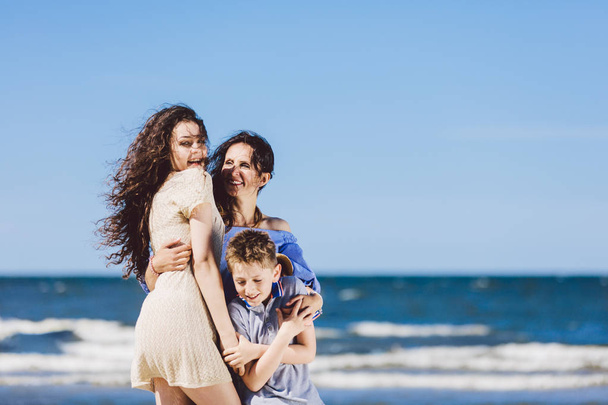Madre, hija e hijo abrazándose en la playa. Tiempo en familia. Vacaciones
. - Foto, Imagen