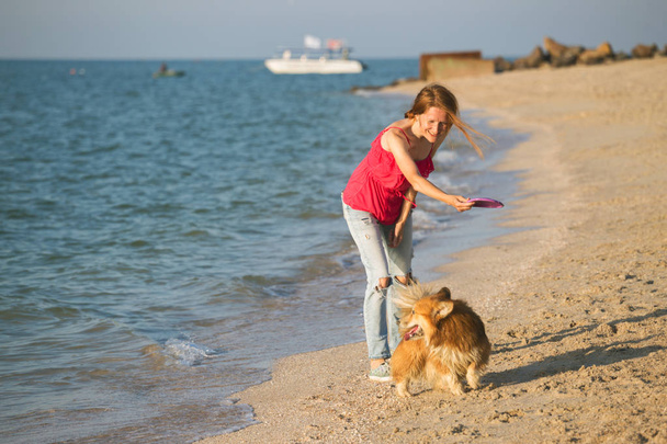 happy fun weekend by the sea - girl playing at the frisbee with a dog on the beach. Summe - Фото, изображение