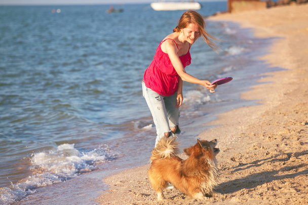 happy fun weekend by the sea - girl playing at the frisbee with a dog on the beach. Summe - Foto, Imagem