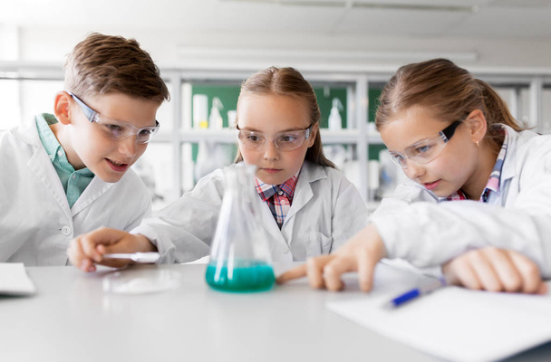 education, science, chemistry and children concept - kids or students with test tube making experiment at school laboratory - Foto, imagen