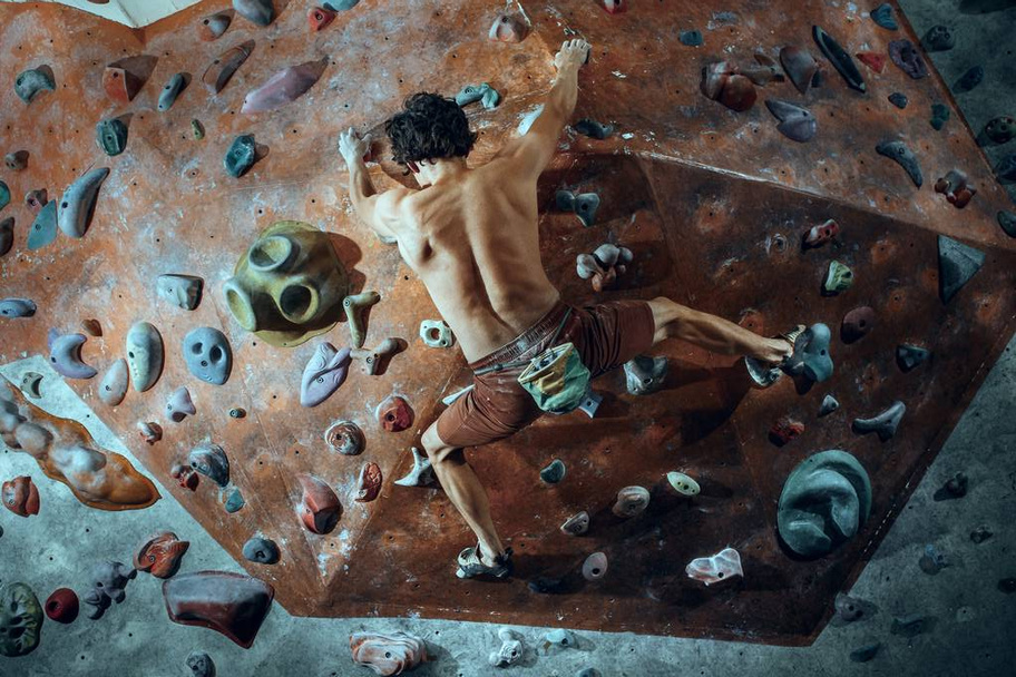 Free climber young man climbing artificial boulder indoors - Fotoğraf, Görsel