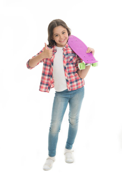 Nice board. Kid girl happy holds penny board. Modern teen hobby. Girl happy face carries penny board white background. Learning how to ride penny board. Child likes plastic skateboard shows thumbs up - Foto, immagini