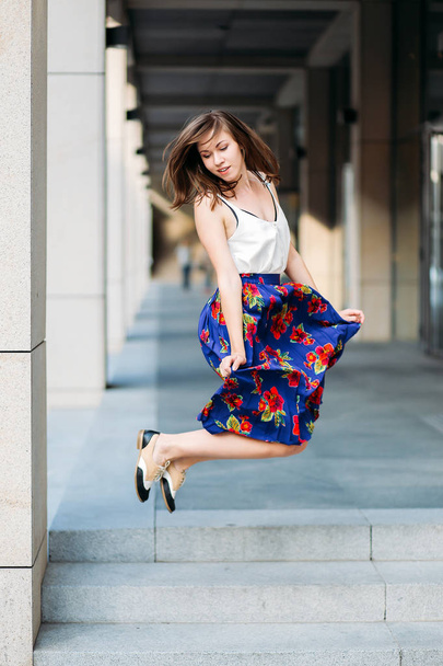 Young beautiful woman jumping on the street, urban background. W - Zdjęcie, obraz