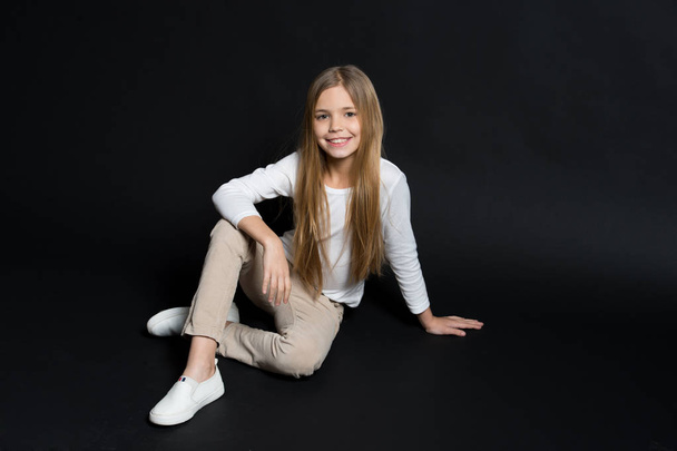 Carefree childhood. Girl long hair cute smiling face relaxing, black background. Child girl carefree enjoy childhood. Model young posing studio. Take advantage carefree childhood, copy space - Photo, image