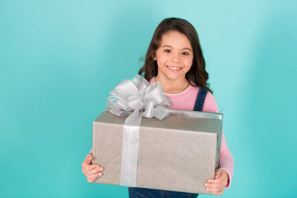 Thank you so much. Child happy face holds big gift box turquoise background. Kid girl delighted gift. Girl curly hairstyle adorable happy face celebrate birthday. Kid happy loves birthday gifts - Photo, image