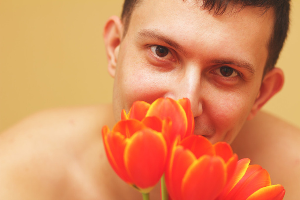 Romantic smiling young man with flowers - Фото, изображение