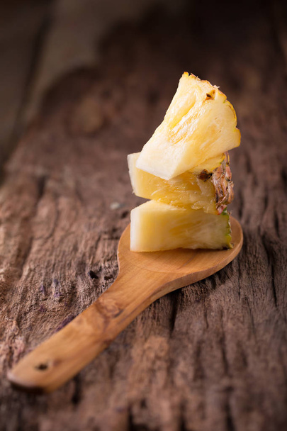 Pineapple slices and pineapple shelled on old wooden background - Foto, afbeelding