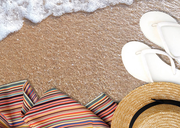 Κάτοψη πέδιλα παραλίας, σκάφη καπέλο και multi χρώμα κασκόλ σε φόντο παραλία με άμμο. Αντιγράψτε το άδειο κενό χώρο για το κείμενο. Hipster διακοπές, καλοκαίρι μέρα διακοπών traval θεματικού concept. - Φωτογραφία, εικόνα