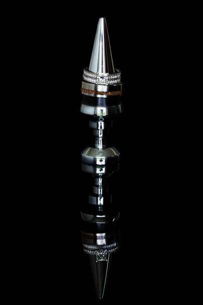 Anéis de casamento empilhados em uma rolha de garrafa contra um fundo preto com um reflexo
 - Foto, Imagem