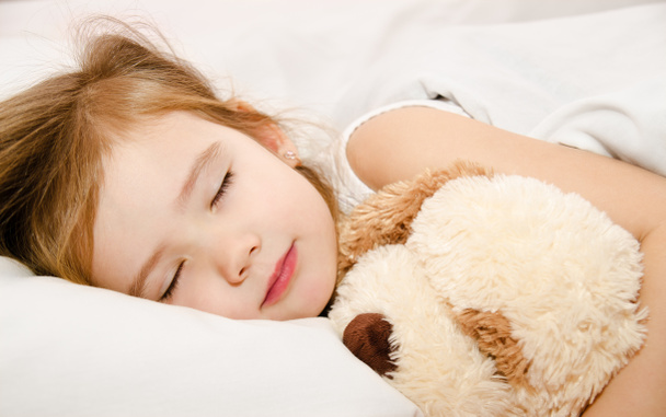 αξιολάτρευτο κοριτσάκι που κοιμάται στο κρεβάτι - Φωτογραφία, εικόνα