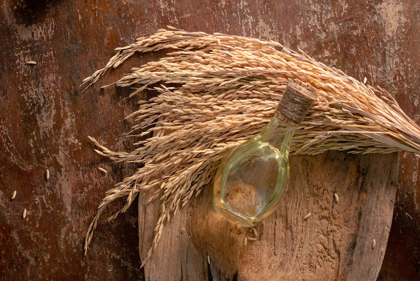 Üveg rizs korpa olaj és unmilled rizs, fából készült háttér - Fotó, kép