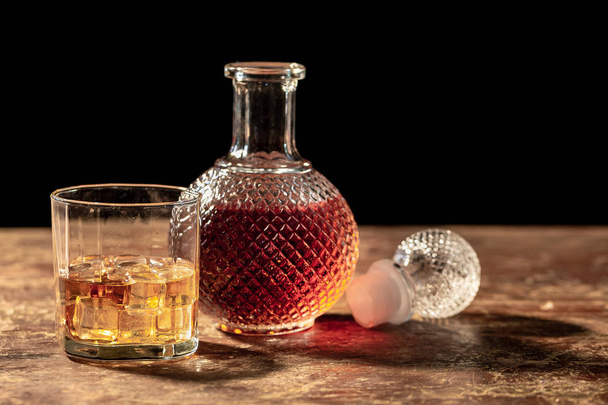 Whisky de botella y vaso de whisky con hielo sobre fondo negro
 - Foto, Imagen