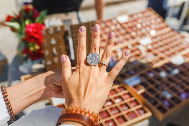 Una mujer probándose su nuevo anillo en el mercado de pulgas al aire libre, joyería y concepto de compras
 - Foto, Imagen