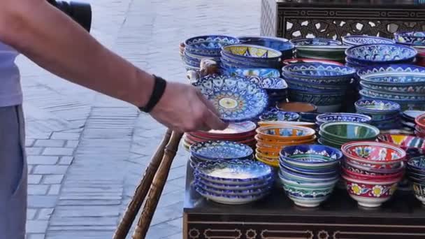 Man Tourist auf dem östlichen Markt. der Mann handelt und wählt keramische Gerichte im orientalischen Stil. - Filmmaterial, Video
