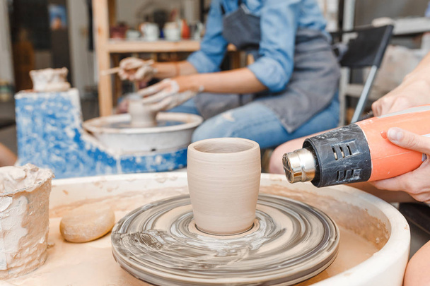 Женщина сушит посуду на гончарном круге во время мастерской
 - Фото, изображение