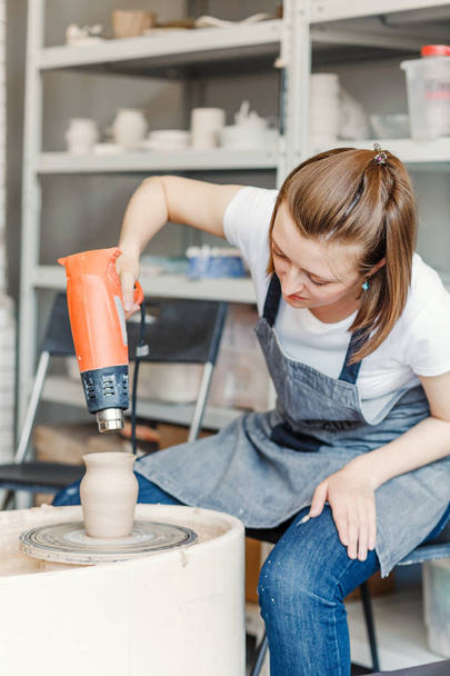 Artiste séchage vient de faire pot de houx sur une roue de poterie en utilisant sèche-linge professionnel
 - Photo, image