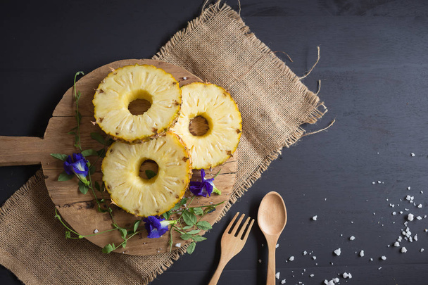 Ananas bio jaune frais coupé en tranches sur une table en bois
. - Photo, image