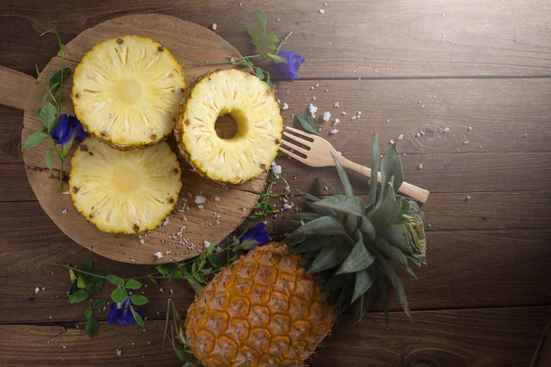 Piña orgánica amarilla fresca cortada en rodajas sobre mesa de madera
. - Foto, Imagen