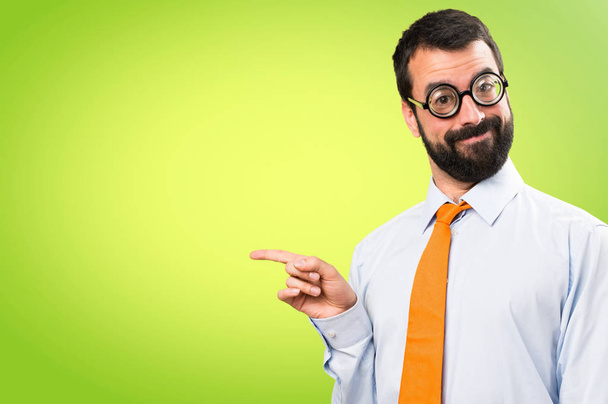 Αστείος άνθρωπος με γυαλιά επισημαίνοντας την πλευρική σε πολύχρωμο φόντο - Φωτογραφία, εικόνα