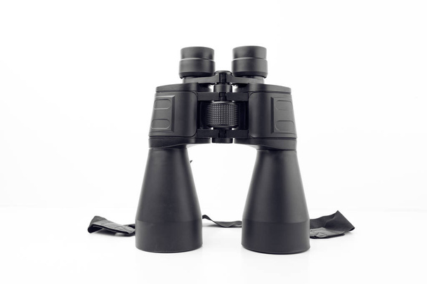 Binóculos pretos com grandes lentes reflexivas em fundo branco liso
 - Foto, Imagem