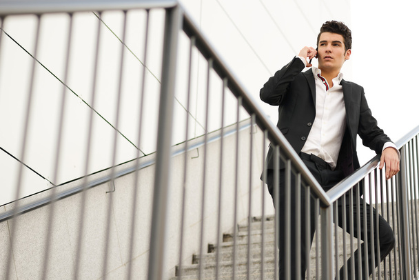 Молодой бизнесмен в офисном здании разговаривает по телефону
 - Фото, изображение
